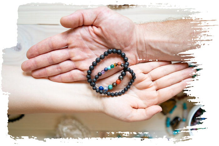 Hands holding a pair of lava stone protection bracelets